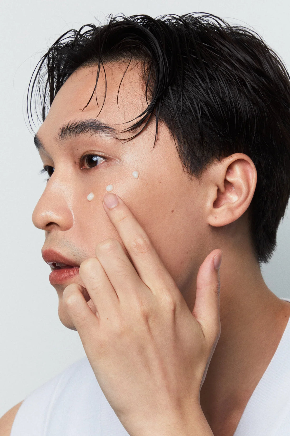 Image of an Asian man applying NAIIAN Beauty's Eye and Face Serum to his cheeks 